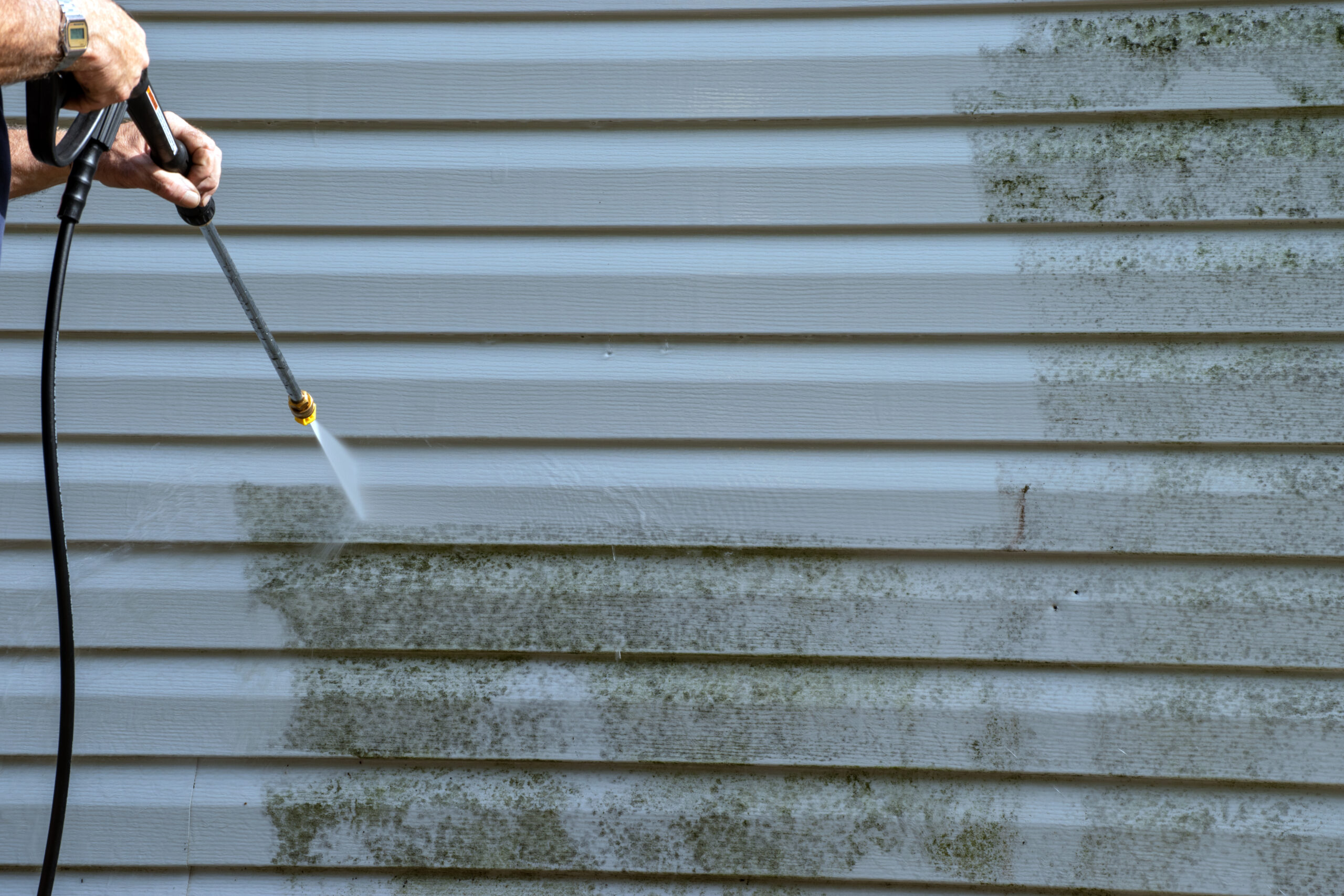 Technician power washes mold and algae from vinyl siding in Westchester NY