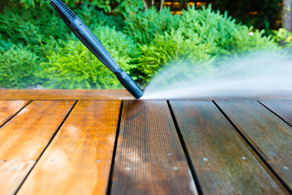 Technician applying final wash to lakeside home’s wood deck